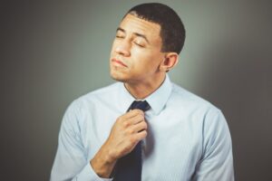 man arranging his black necktie