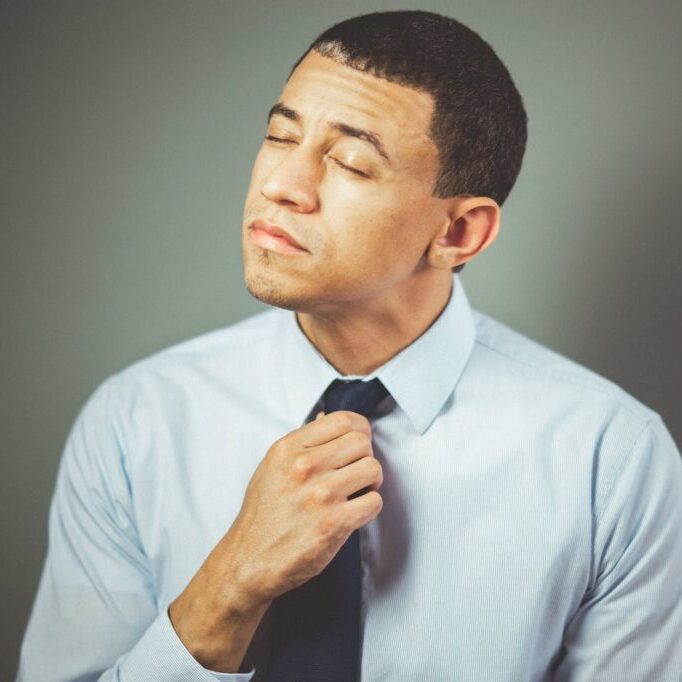 man arranging his black necktie