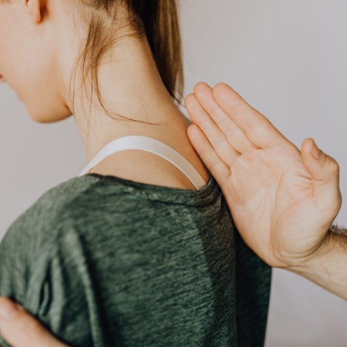 crop unrecognizable orthopedist checking up back of woman in clinic